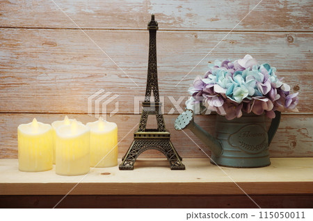 Home decor Eiffel tower, LED candle light and artificial flower in flower pot on wooden shelve background Home decor Eiffel tower, LED candle light and artificial flower in flower pot on wooden shelve background 115050011