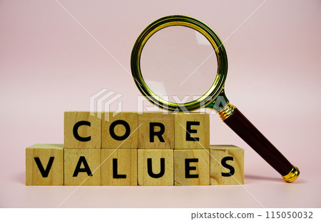 Core Values with wooden blocks alphabet letters and Magnifying glass on pink background 115050032