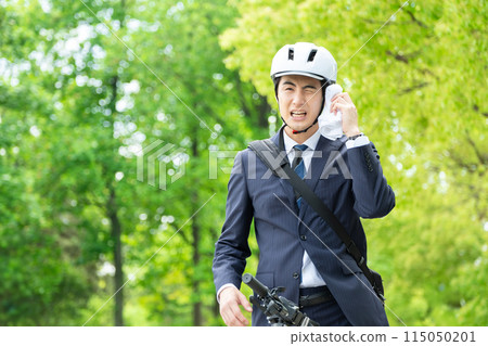 A businessman commuting by bicycle wiping off sweat 115050201