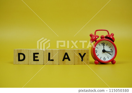Delay with wooden blocks alphabet letters and alarm clock on yellow background Delay with wooden blocks alphabet letters and alarm clock on yellow background 115050380