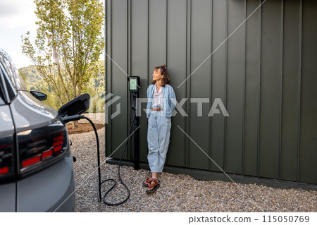 Woman waits for electric car to be charged 115050769