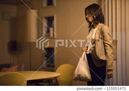 一位女商人回家後在客廳脫掉夾克的夜間例行公事 一位女商人回家後在客廳脫掉夾克的夜間例行公事 115051471