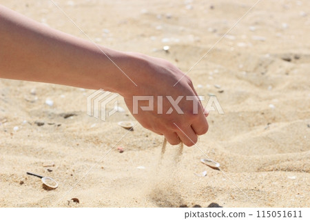 Hands holding sand on the beach, sand falling from hands 115051611