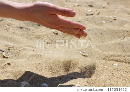 Hands holding sand on the beach, sand falling from hands 115051612