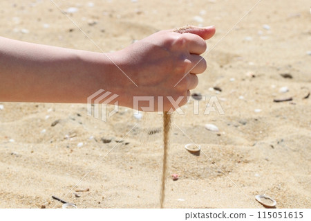 Hands holding sand on the beach, sand falling from hands Hands holding sand on the beach, sand falling from hands 115051615