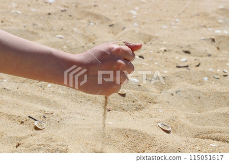 Hands holding sand on the beach, sand falling from hands Hands holding sand on the beach, sand falling from hands 115051617