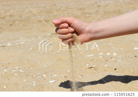 Hands holding sand on the beach, sand falling from hands Hands holding sand on the beach, sand falling from hands 115051625