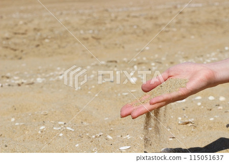 沙灘上一隻手握著沙子，沙子落在手裡 115051637