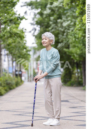Senior woman standing with a cane 115051989