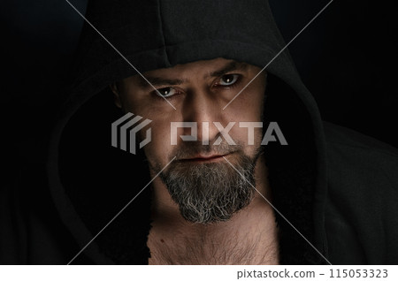 Mysterious man wearing hoodies on a dark background. Handsome model wearing black hoodie on a plain black background Mysterious man wearing hoodies on a dark background. Handsome model wearing black hoodie on a plain black background 115053323