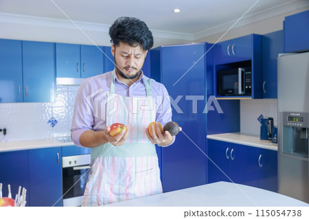 一個穿著圍裙拿著蘋果和酪梨的男人 一個穿著圍裙拿著蘋果和酪梨的男人 115054738