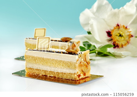 Slices of sponge cake with vanilla cream and almond on blue background 115056259