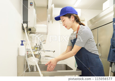 穿著圍裙的女工作人員在廚房洗手 115056577
