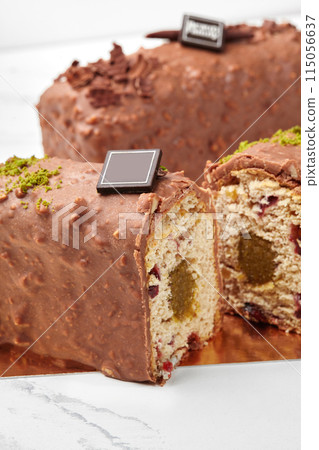 Sliced chocolate covered loaf cake with fruit jelly, dried cranberries and pistachio Sliced chocolate covered loaf cake with fruit jelly, dried cranberries and pistachio 115056637