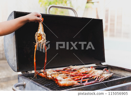 Grills king prawns on charcoal grill in the restaurant. Grills king prawns on charcoal grill in the restaurant. 115056905