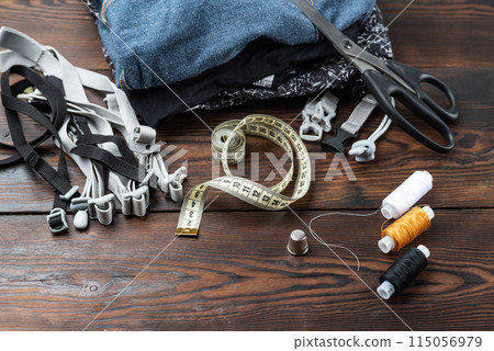Sewing supplies and materials. Sewing workshop. Clothes and threads on the table. Sewing supplies and materials. Sewing workshop. Clothes and threads on the table. 115056979