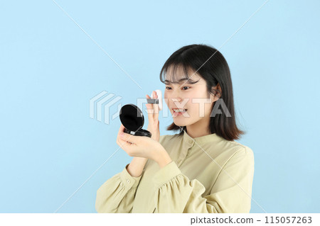 Young woman putting on makeup, makeup powder 115057263