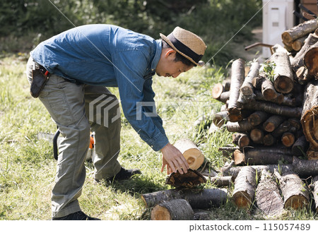 Man cutting wood with a chainsaw 115057489
