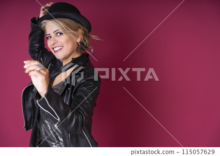 A woman in a black jacket and hat is smiling and posing for a photo 115057629