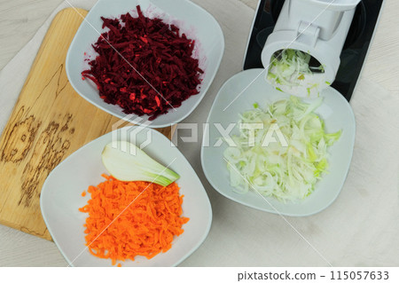 Onion, carrot and beet in a vegetable cutter on kitchen. Chopped onion is falling into a bowl. Homemade healthy food. Health line. 115057633