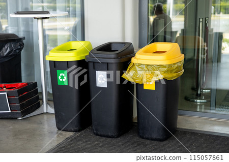 Colorful trash cans for sorting garbage. For plastic, glass, paper and others waste. Waste containers for garbage segregation in Poland, standing next to a wall Colorful trash cans for sorting garbage. For plastic, glass, paper and others waste. Waste containers for garbage segregation in Poland, standing next to a wall 115057861