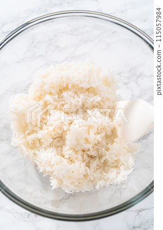 Cilantro Lime Rice. Mixing ingredients in a glass mixing bowl to prepare cilantro lime rice. 115057984