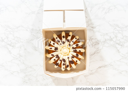 Flat lay. Packaging the freshly baked pumpkin bundt cake into a white paper box for gifting. Flat lay. Packaging the freshly baked pumpkin bundt cake into a white paper box for gifting. 115057990