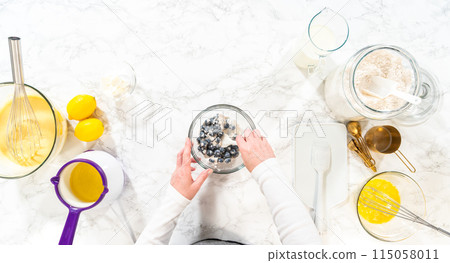 Flat lay. Integrating ingredients in a glass bowl, adeptly stirring with a whisk to craft a tantalizing lemon-blueberry bundt cake. 115058011