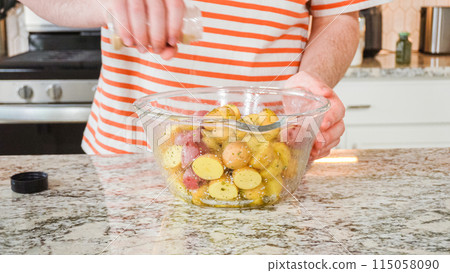 In a sleek, modern kitchen, a young man attentively prepares dinner. His current task involves carefully seasoning small rainbow potatoes in a glass bowl, promising a flavorful meal ahead. In a sleek, modern kitchen, a young man attentively prepares dinner. His current task involves carefully seasoning small rainbow potatoes in a glass bowl, promising a flavorful meal ahead. 115058090