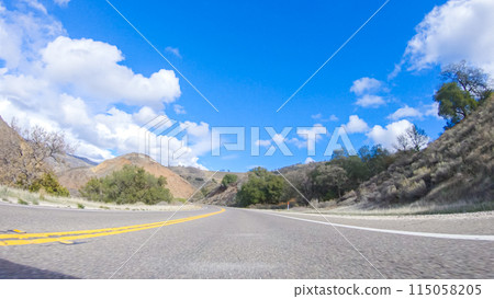 Vehicle is cruising along the Cuyama Highway under the bright sun. The surrounding landscape is illuminated by the radiant sunshine, creating a picturesque and inviting scene as the car travels Vehicle is cruising along the Cuyama Highway under the bright sun. The surrounding landscape is illuminated by the radiant sunshine, creating a picturesque and inviting scene as the car travels 115058205