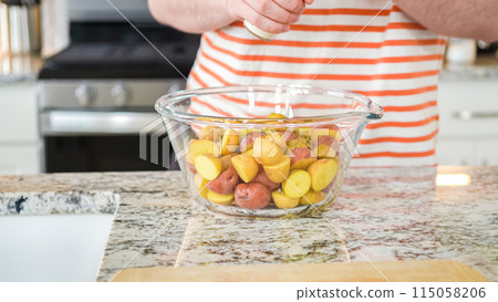 In a sleek, modern kitchen, a young man attentively prepares dinner. His current task involves carefully seasoning small rainbow potatoes in a glass bowl, promising a flavorful meal ahead. In a sleek, modern kitchen, a young man attentively prepares dinner. His current task involves carefully seasoning small rainbow potatoes in a glass bowl, promising a flavorful meal ahead. 115058206