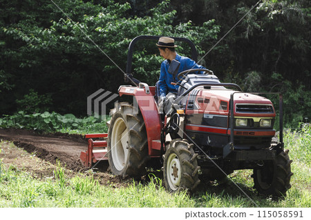 Young man plowing the field with a tractor 115058591