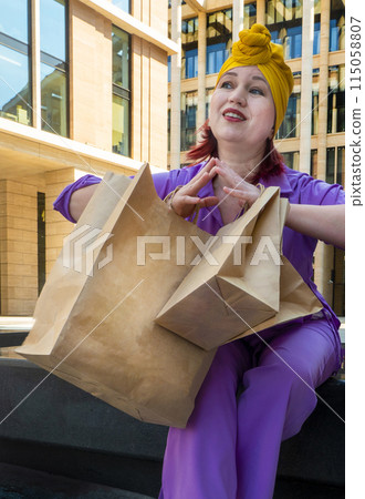 woman with craft shopping bags in the city. The concept of fashionable Consumerism and ecology. woman with craft shopping bags in the city. The concept of fashionable Consumerism and ecology. 115058807