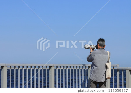 Man holding a camera Man taking pictures with a telephoto lens Man holding a camera Man taking pictures with a telephoto lens 115059527