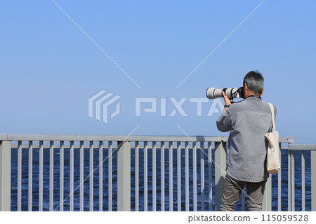 Man holding a camera Man taking pictures with a telephoto lens Man holding a camera Man taking pictures with a telephoto lens 115059528