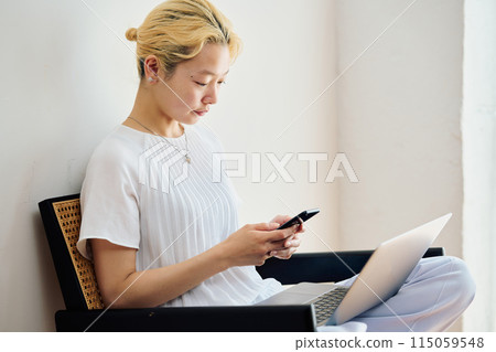 一位女士在家中操作智慧型手機 一位女士在家中操作智慧型手機 115059548