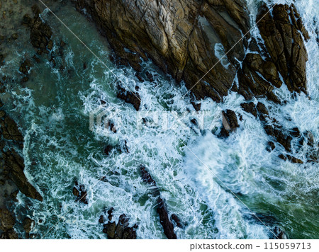 Bird eye view seashore with big wave crashing on rock cliff. Beautiful waves sea surface in sunny day summer background, Amazing seascape top view seacoast landscape view Bird eye view seashore with big wave crashing on rock cliff. Beautiful waves sea surface in sunny day summer background, Amazing seascape top view seacoast landscape view 115059713