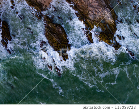 Bird eye view seashore with big wave crashing on rock cliff. Beautiful waves sea surface in sunny day summer background, Amazing seascape top view seacoast landscape view Bird eye view seashore with big wave crashing on rock cliff. Beautiful waves sea surface in sunny day summer background, Amazing seascape top view seacoast landscape view 115059728