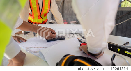 Engineer working on blueprint at construction site, detail of hands and tools. colleagues discussion concept 115061214