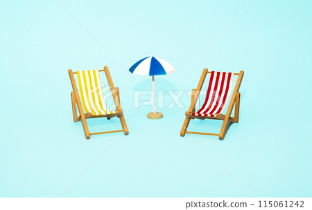 Beach relaxation and vacation concept. Toy sun lounger and umbrella on blue colorful paper background. Beach relaxation and vacation concept. Toy sun lounger and umbrella on blue colorful paper background. 115061242