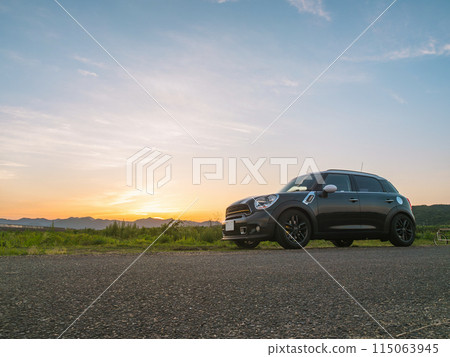 An imported car parked with the setting sun in the background An imported car parked with the setting sun in the background 115063945