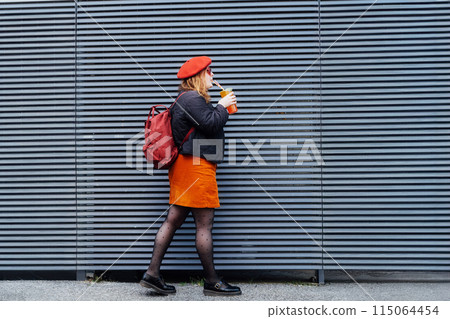 Smiling plus size woman in heart shaped sunglasses and bright clothes drinking sugar flavored tapioca bubble tea near striped urban wall. Happy fashionable hipster overweight girl. Street fashion. 115064454