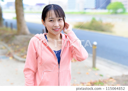 A young woman walking while listening to music with wired earphones Body makeup Trimming A young woman walking while listening to music with wired earphones Body makeup Trimming 115064852