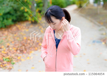 A young woman walking while listening to music with wired earphones Body makeup Trimming A young woman walking while listening to music with wired earphones Body makeup Trimming 115064854