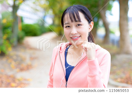 A young woman walking while listening to music with wired earphones Body makeup Trimming 115065053