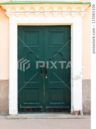 Vintage green wooden door in yellow stone wall 115065106