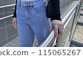Young woman in jeans holds her hand on metal handrail on street ramp, woman hand grabs for balance on the stairs 115065267