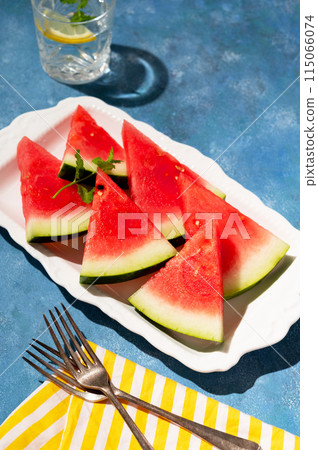 Slices of watermelon in a plate, blue background. Healthy food 115066074