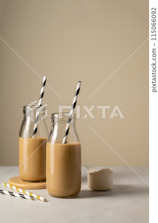 Chocolate protein drinks in glass bottles with paper straw. Chocolate protein drinks in glass bottles with paper straw. 115066092