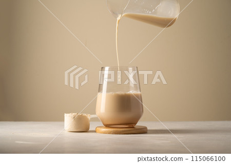 Protein powder. Pouring chocolate drink in a glass. 115066100